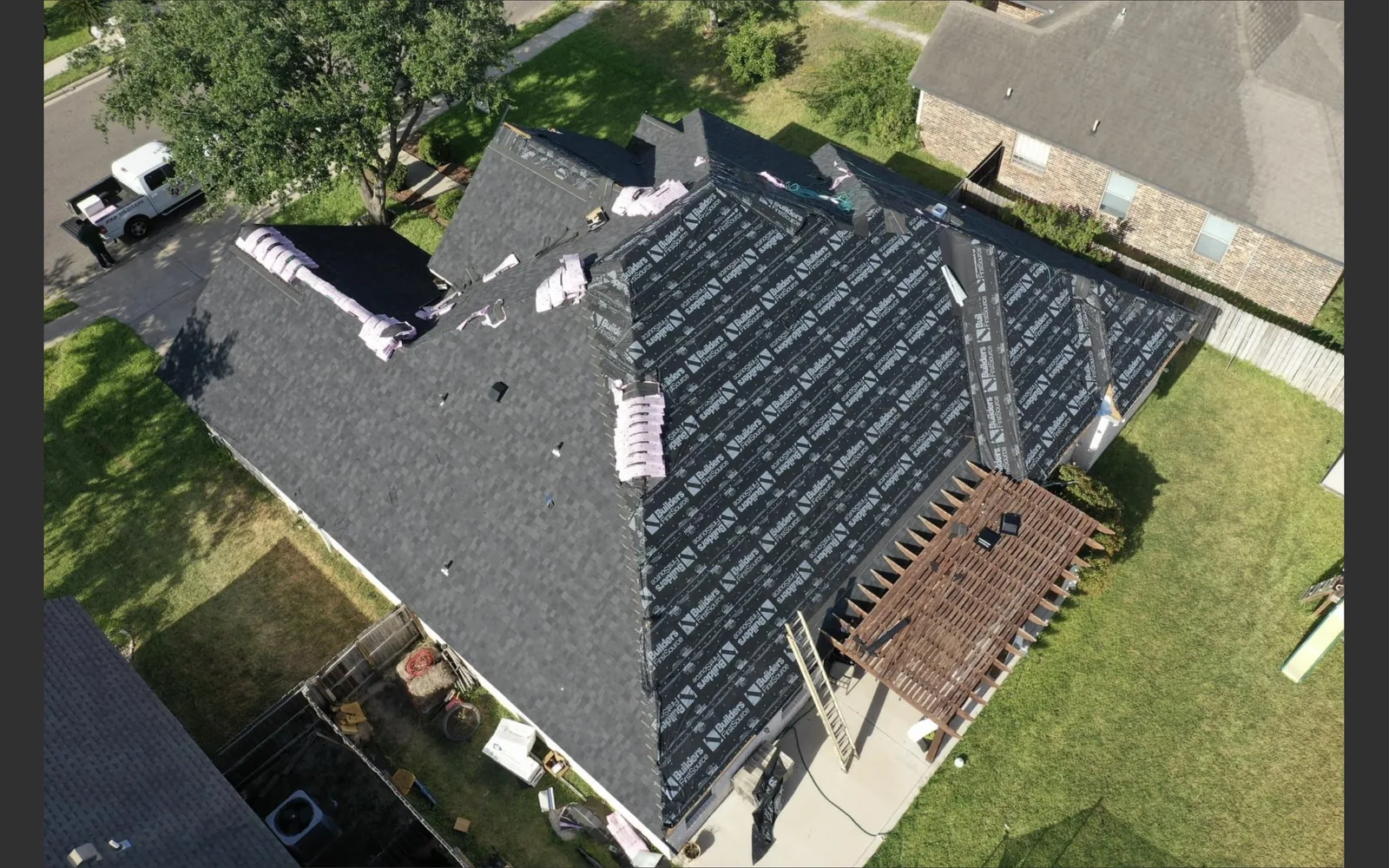 Aerial view of the same The Woodlands roof during installation, with underlayment and shingle bundles visible